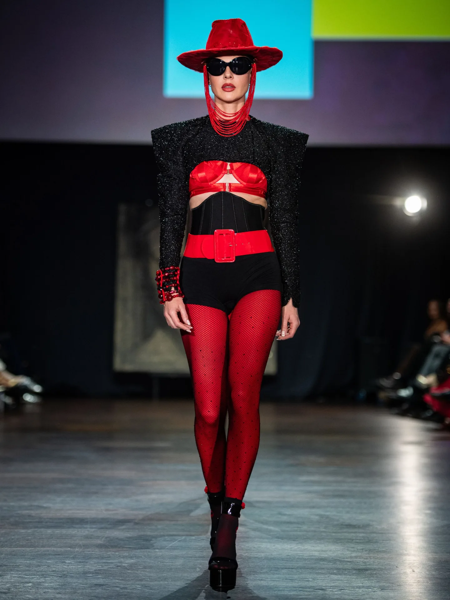 Model wearing red and black outfit with a red wide-brimmed hat by Jean Luc Amsler on the CFN 4.0 runway