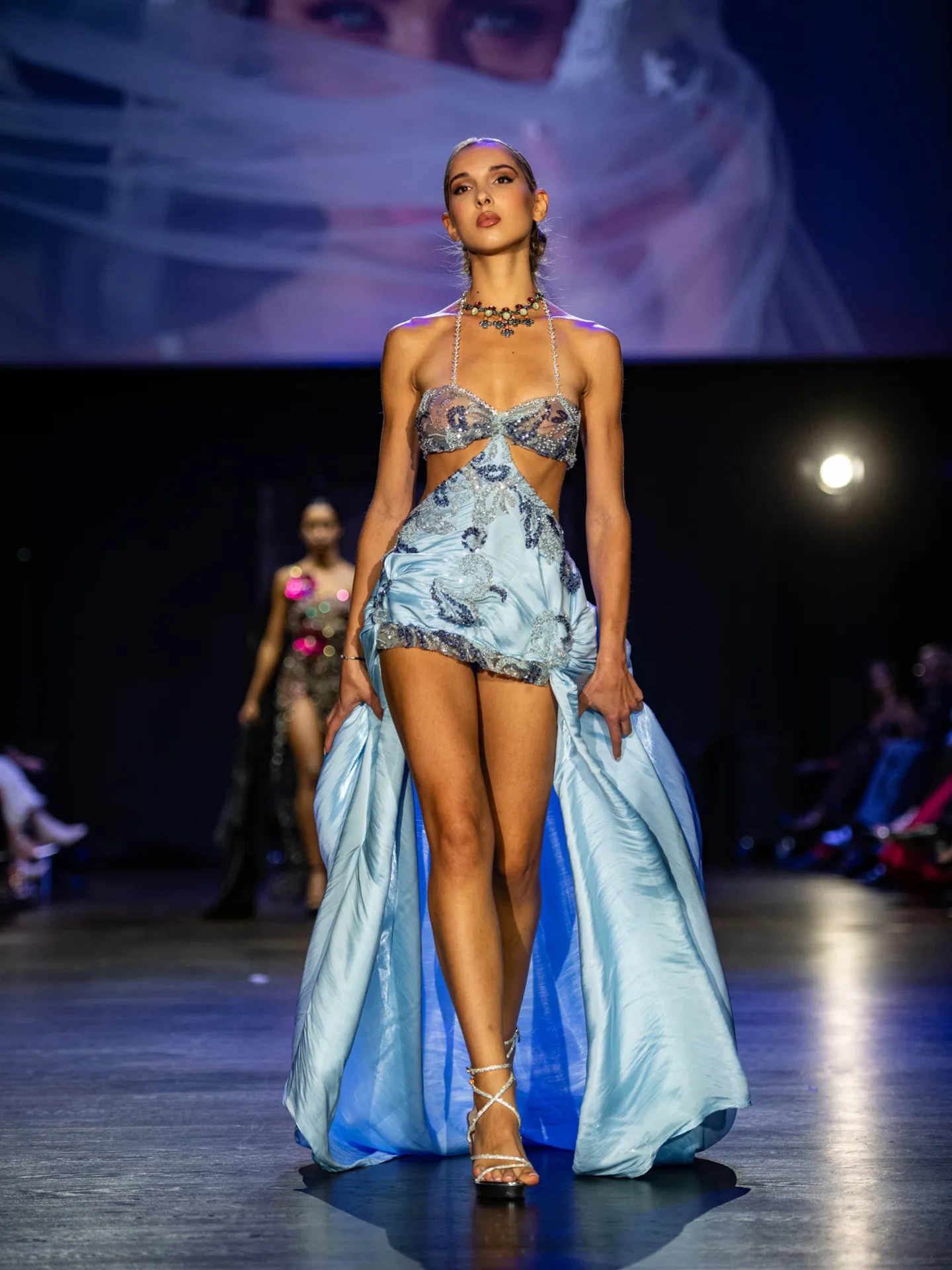 Model wearing a blue embellished two-piece outfit with a train by Kenu Boutique on the CFN 4.0 runway