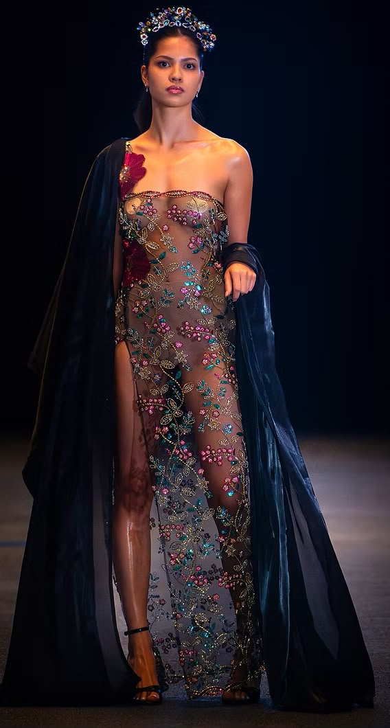 Model in an embroidered couture gown with a dark cape on the Couture Fashion Night runway